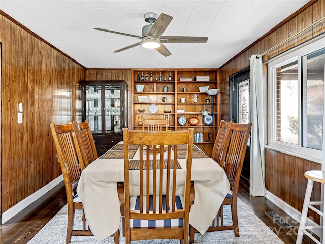 dining area with built in shelves, ceiling fan, dark hardwood / wood-style flooring, and wood walls