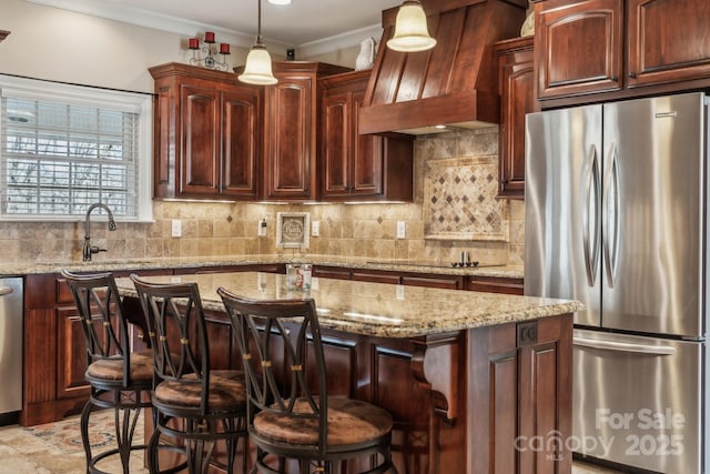 kitchen with custom exhaust hood, appliances with stainless steel finishes, tasteful backsplash, a breakfast bar, and a center island