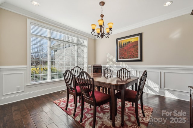 dining space with dark wood-type flooring, an inviting chandelier, a healthy amount of sunlight, and crown molding