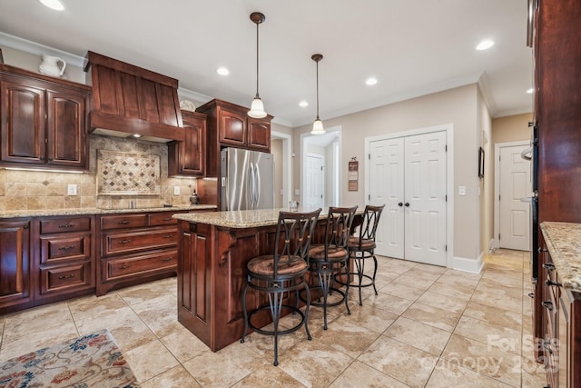 kitchen featuring light stone countertops, a center island, tasteful backsplash, and stainless steel refrigerator