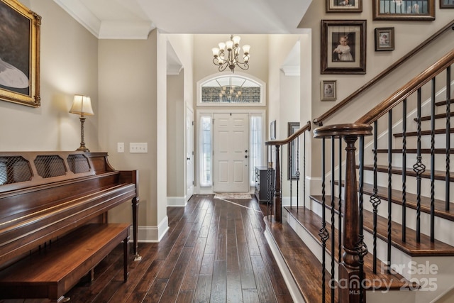 entryway with dark hardwood / wood-style flooring, ornamental molding, and a notable chandelier