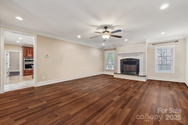 unfurnished living room featuring crown molding, wood finished floors, baseboards, and ceiling fan