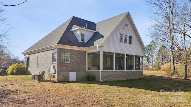 back of property with a yard, central AC, a sunroom, a shingled roof, and brick siding