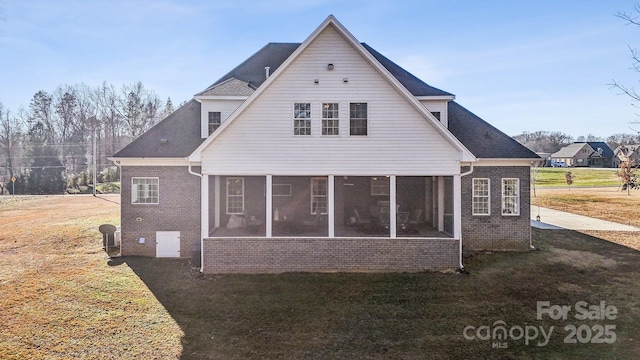 back of house with a lawn, brick siding, and a sunroom