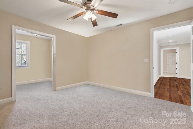 empty room with visible vents, carpet flooring, baseboards, and ceiling fan