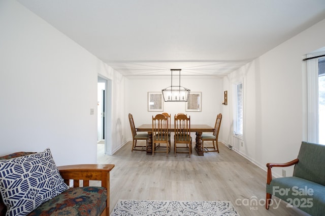 dining space featuring light wood-type flooring and a notable chandelier