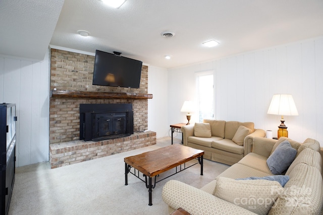 carpeted living room with a fireplace, wood walls, a textured ceiling, and ornamental molding