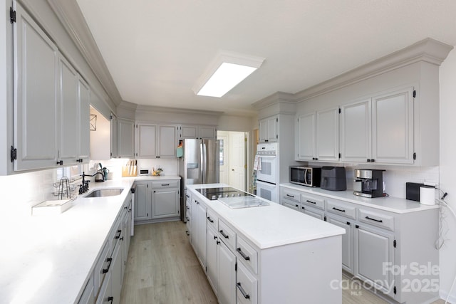 kitchen with stainless steel appliances, white cabinets, a center island, and sink