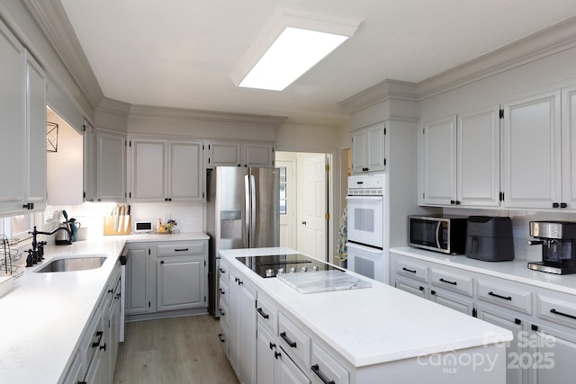 kitchen featuring a center island, sink, light hardwood / wood-style flooring, stainless steel appliances, and white cabinets