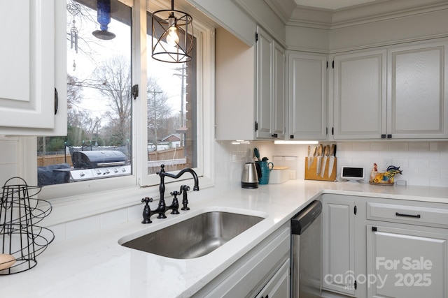 kitchen with stainless steel dishwasher, decorative backsplash, sink, white cabinetry, and hanging light fixtures