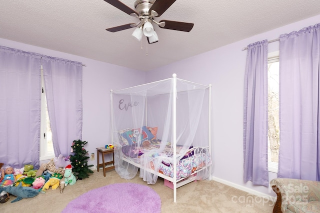 carpeted bedroom with ceiling fan and a textured ceiling