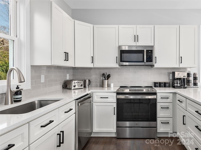 kitchen featuring sink, stainless steel appliances, light stone counters, dark hardwood / wood-style floors, and white cabinets