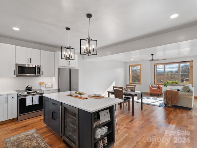 kitchen featuring hanging light fixtures, beverage cooler, stainless steel appliances, light hardwood / wood-style flooring, and a kitchen island