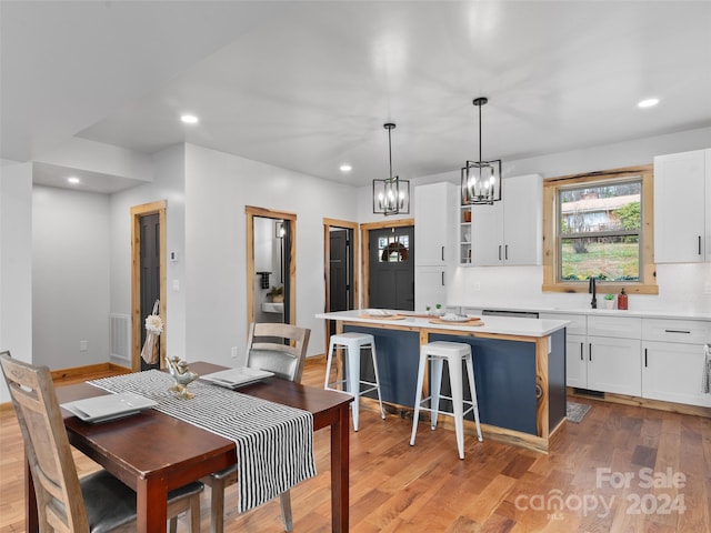 kitchen featuring white cabinets, a kitchen island, light hardwood / wood-style floors, and decorative light fixtures