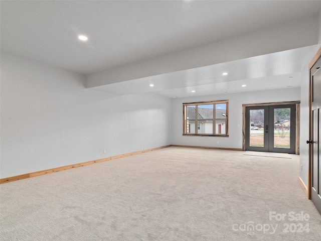 spare room featuring french doors and light colored carpet