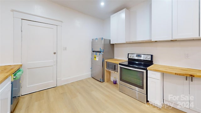 kitchen featuring wooden counters, appliances with stainless steel finishes, and white cabinetry