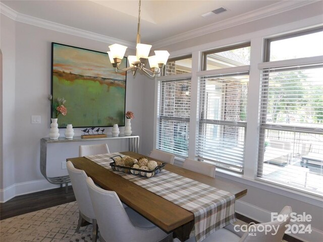 dining area featuring hardwood / wood-style floors, ornamental molding, and an inviting chandelier