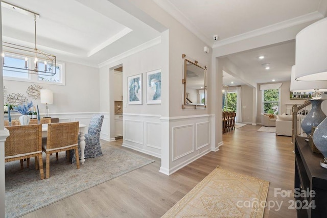 dining space with crown molding, light hardwood / wood-style flooring, and an inviting chandelier