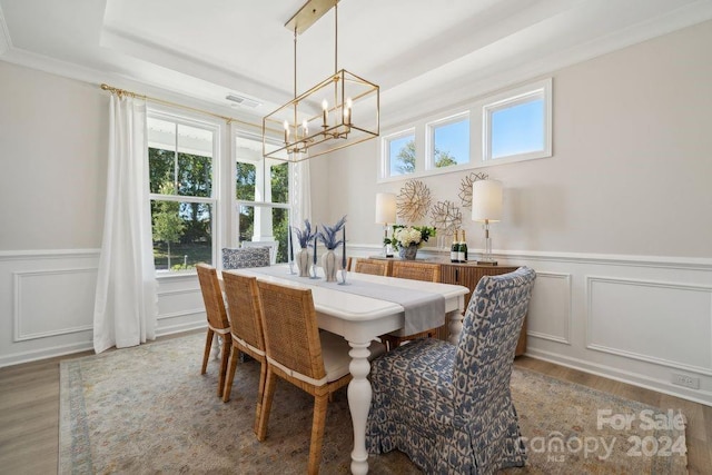 dining room with hardwood / wood-style flooring, a raised ceiling, a wealth of natural light, and a chandelier