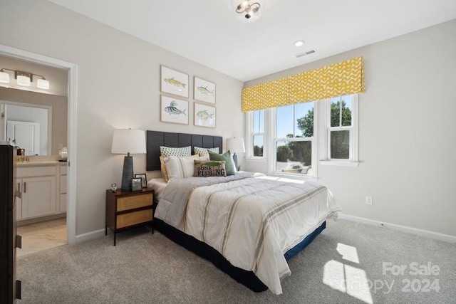 bedroom featuring connected bathroom and light carpet