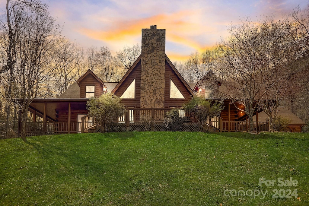 back house at dusk featuring a yard and a deck