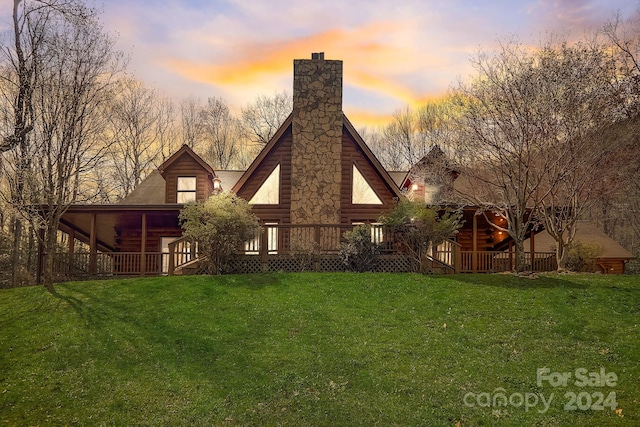 back house at dusk featuring a yard and a deck