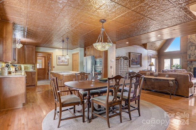 dining area featuring a fireplace, vaulted ceiling, and light wood-type flooring