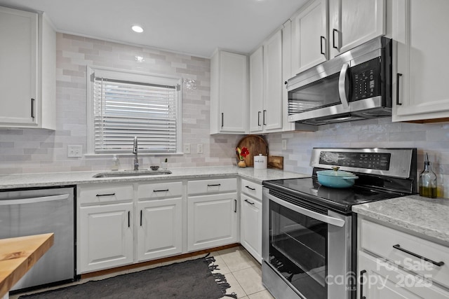 kitchen with white cabinetry, sink, light stone counters, light tile patterned flooring, and appliances with stainless steel finishes