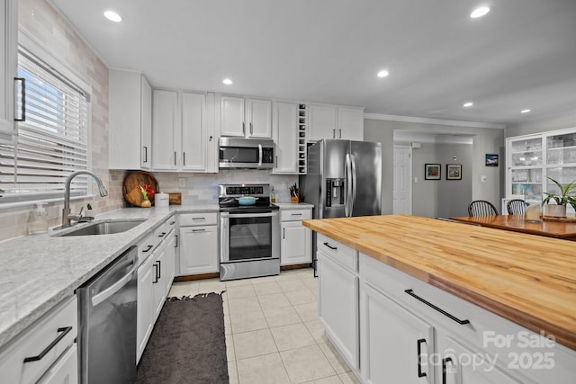 kitchen with decorative backsplash, stainless steel appliances, sink, white cabinetry, and light tile patterned flooring