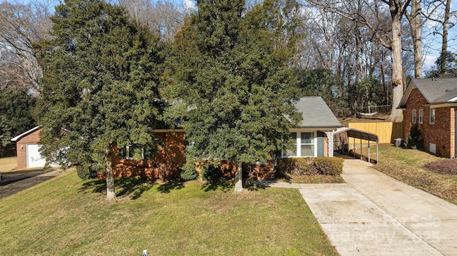 view of property hidden behind natural elements with a carport, a garage, an outbuilding, and a front lawn