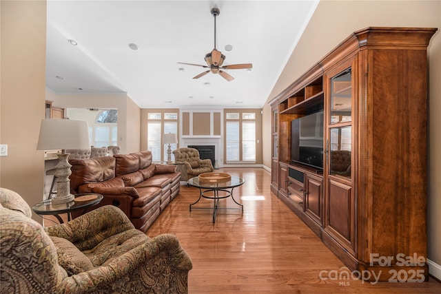 living room featuring built in shelves, ceiling fan, light hardwood / wood-style flooring, and crown molding