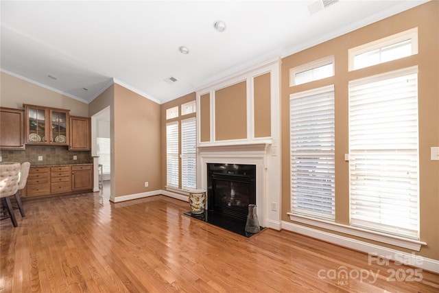 unfurnished living room featuring lofted ceiling, light hardwood / wood-style floors, and ornamental molding