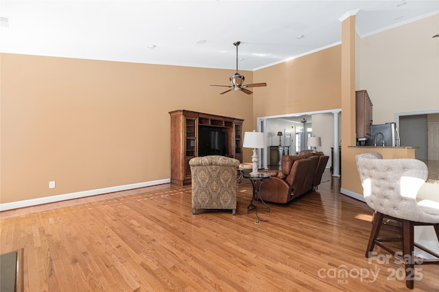 living room featuring light hardwood / wood-style flooring, ceiling fan, and crown molding