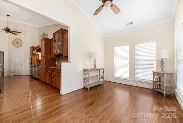 unfurnished living room featuring hardwood / wood-style flooring, ceiling fan, and crown molding