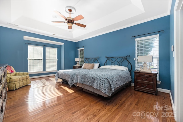 bedroom with a raised ceiling, ceiling fan, and dark hardwood / wood-style flooring