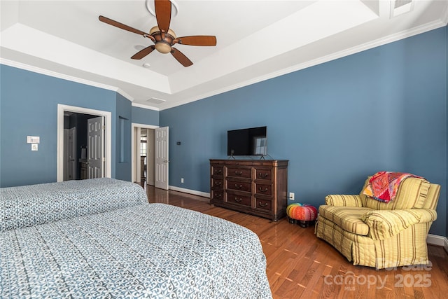 bedroom featuring a tray ceiling, ceiling fan, ornamental molding, and hardwood / wood-style flooring