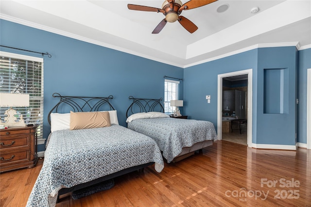 bedroom featuring ensuite bath, ornamental molding, a tray ceiling, ceiling fan, and hardwood / wood-style floors