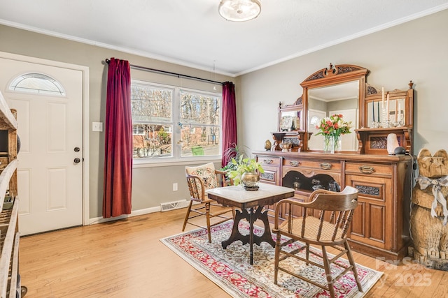 dining area featuring ornamental molding and light hardwood / wood-style flooring