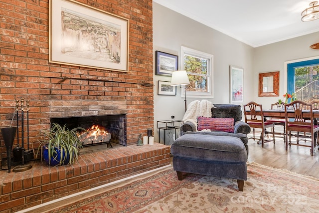 living area with hardwood / wood-style floors, a brick fireplace, and crown molding