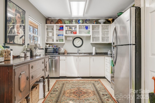 kitchen with stainless steel appliances, white cabinets, sink, and dark stone counters