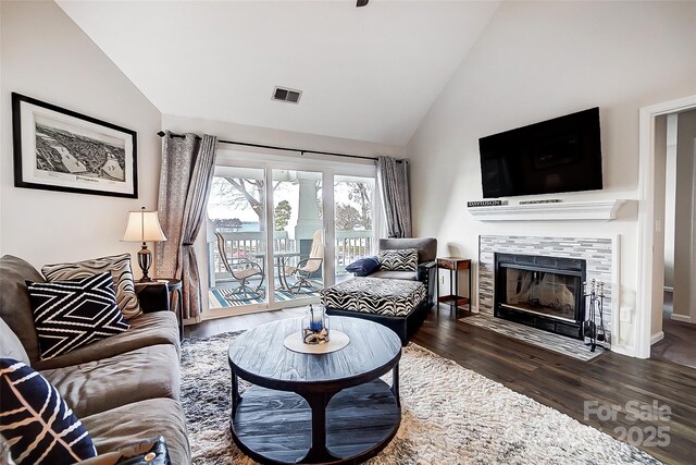 living room with a tile fireplace, lofted ceiling, and dark wood-type flooring