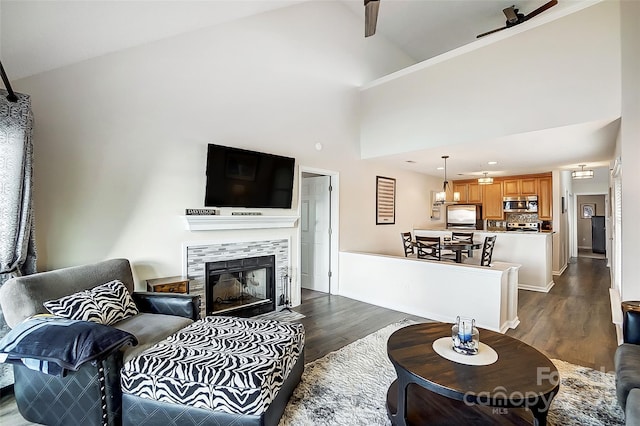 living room with dark wood-type flooring, a fireplace, and high vaulted ceiling