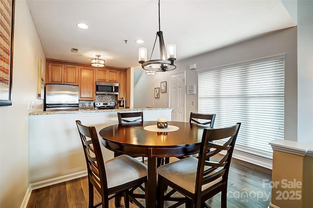 dining area with sink, a chandelier, and dark hardwood / wood-style flooring