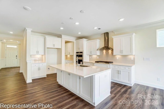 kitchen featuring wall chimney exhaust hood, dark hardwood / wood-style floors, white cabinetry, and an island with sink