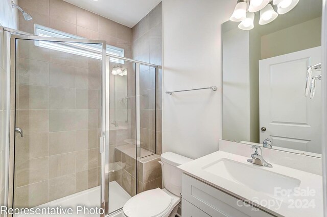 bathroom featuring vanity, toilet, and a shower with door