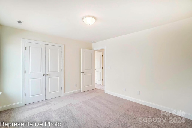 unfurnished bedroom featuring light colored carpet and a closet