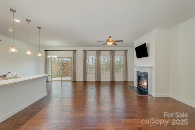 unfurnished living room featuring plenty of natural light, dark wood-style flooring, and a glass covered fireplace