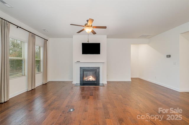 unfurnished living room featuring ceiling fan, visible vents, wood finished floors, and a glass covered fireplace