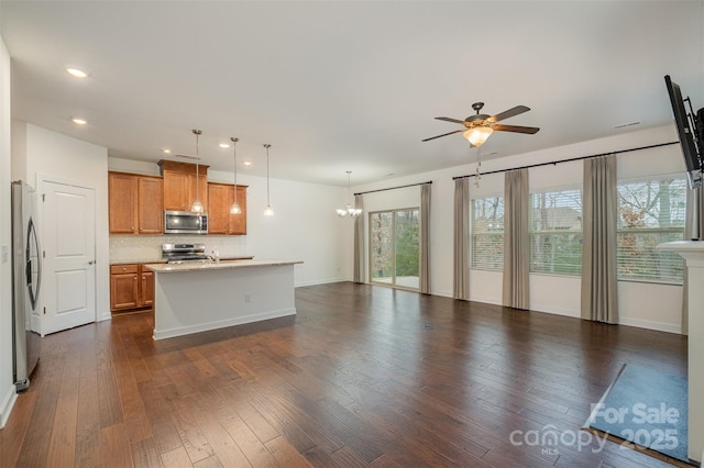 kitchen featuring backsplash, appliances with stainless steel finishes, dark wood-type flooring, open floor plan, and brown cabinetry