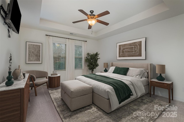 bedroom featuring a raised ceiling, carpet flooring, ceiling fan, and visible vents